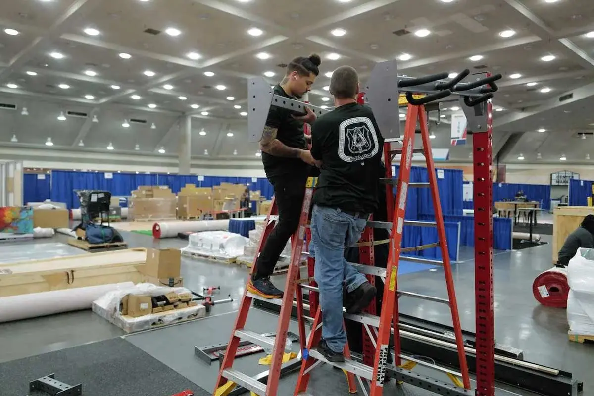 UBC members work from ladders while assembling a tradeshow-style structure in a hands-on training environment.