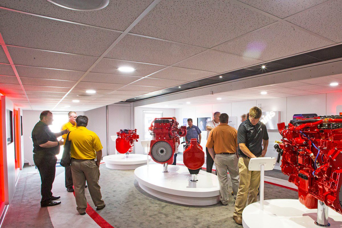 Visitors explore a custom mobile display environment with red engine exhibits.