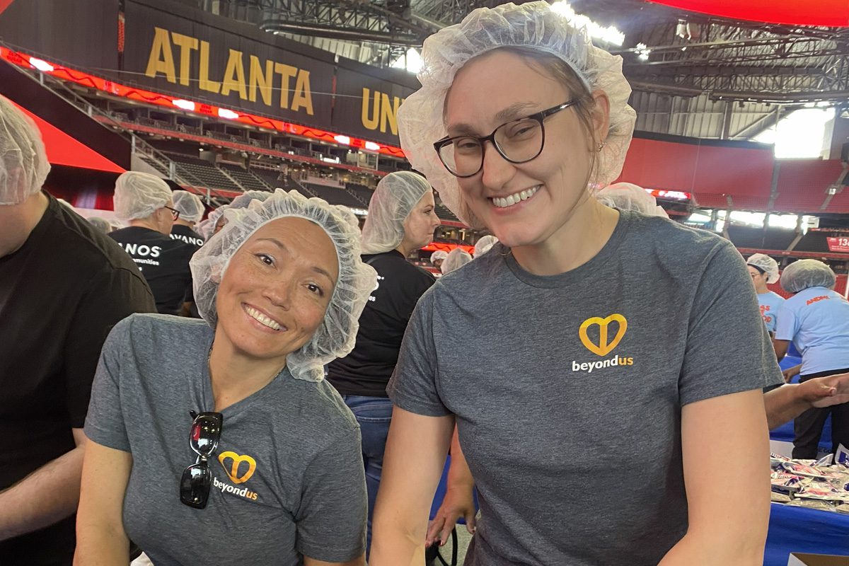 Two experiential marketing team members volunteer at a meal-packing event.