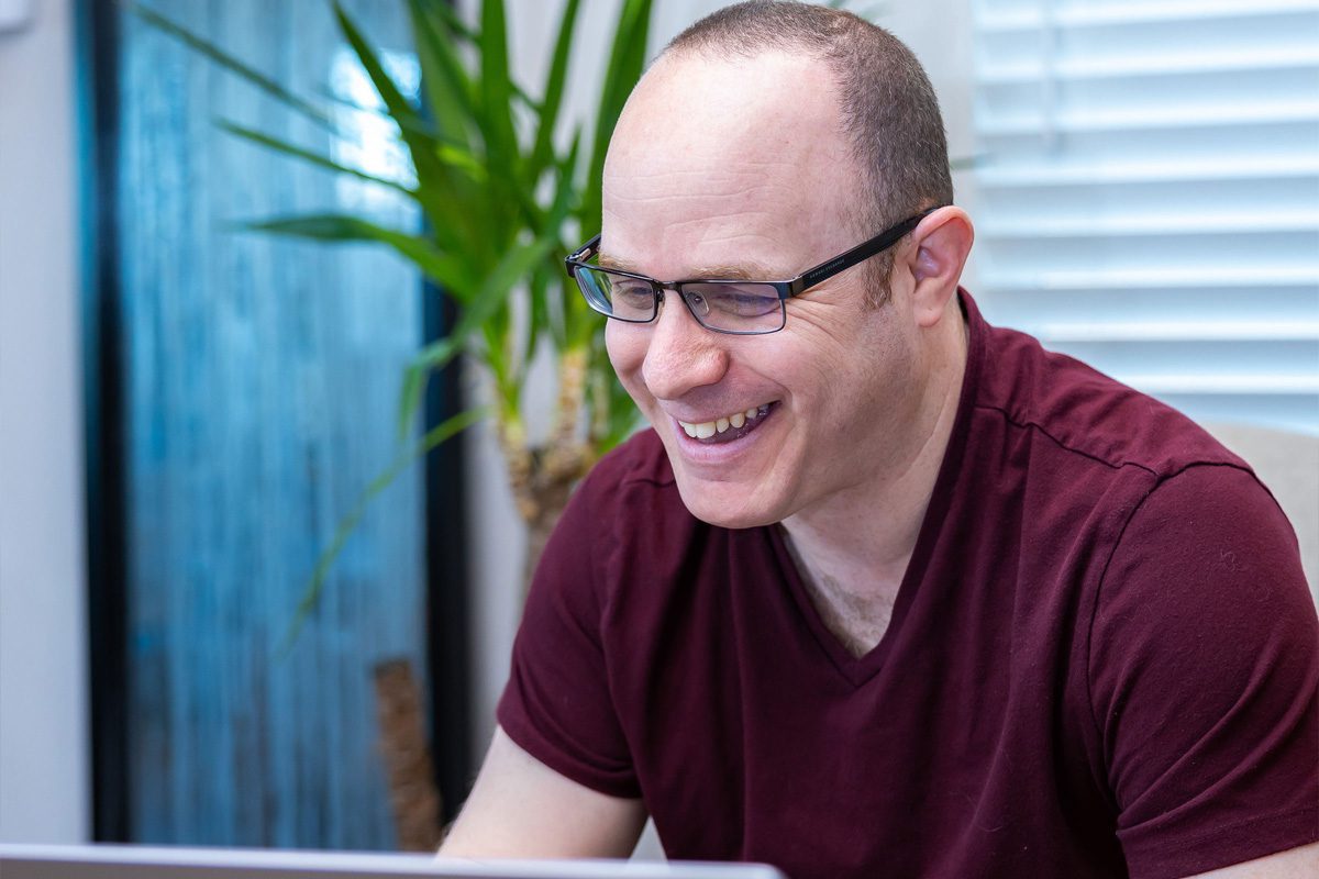 Ran Zookin, founder and managing member of ESM Pros, smiles while working at a laptop.