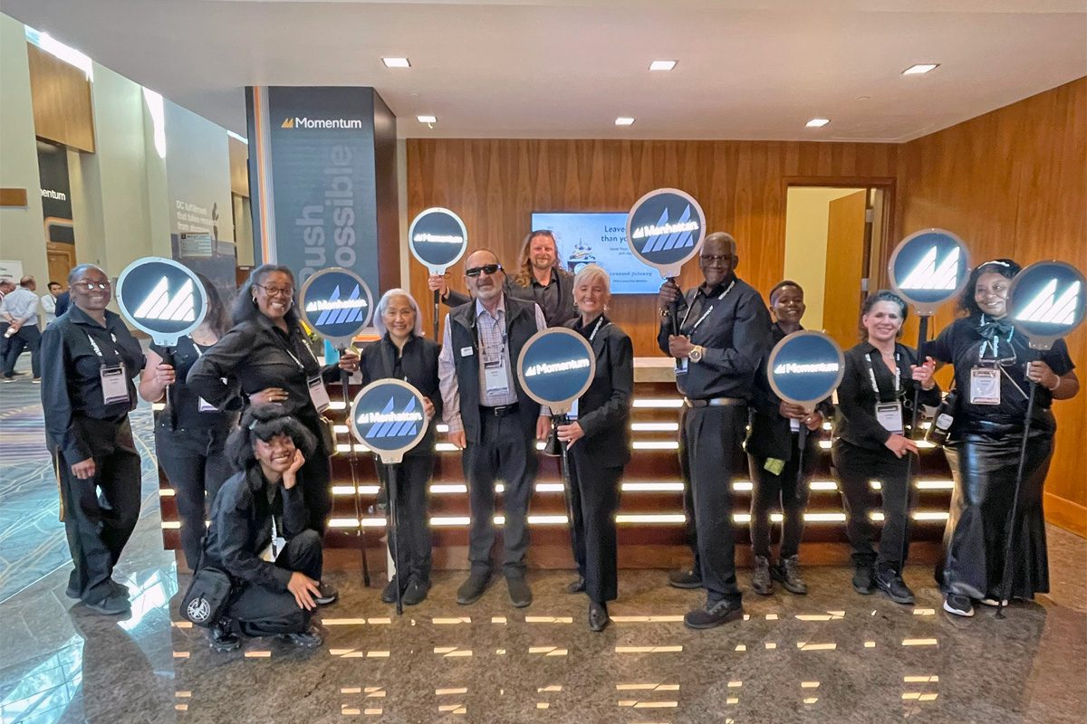 ESM Pros team members pose with Momentum signs during an event.