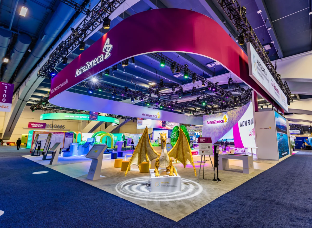 AstraZeneca sustainable exhibit with suspended branding, interactive kiosks, and a large dragon display