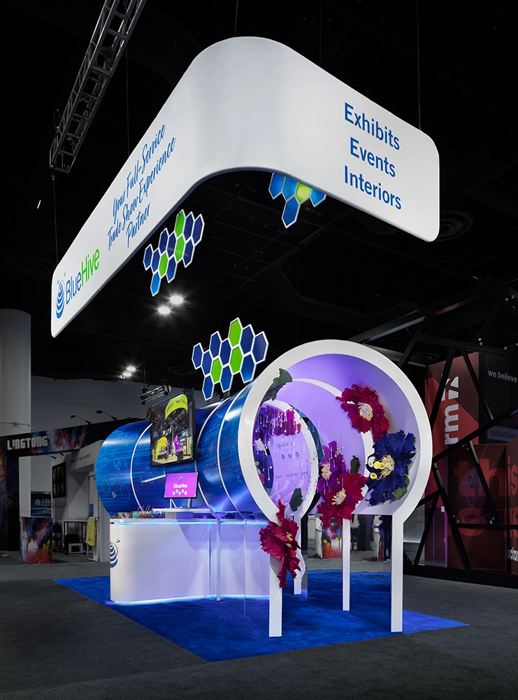 BlueHive small island exhibit with suspended signage, illuminated displays, and floral design elements