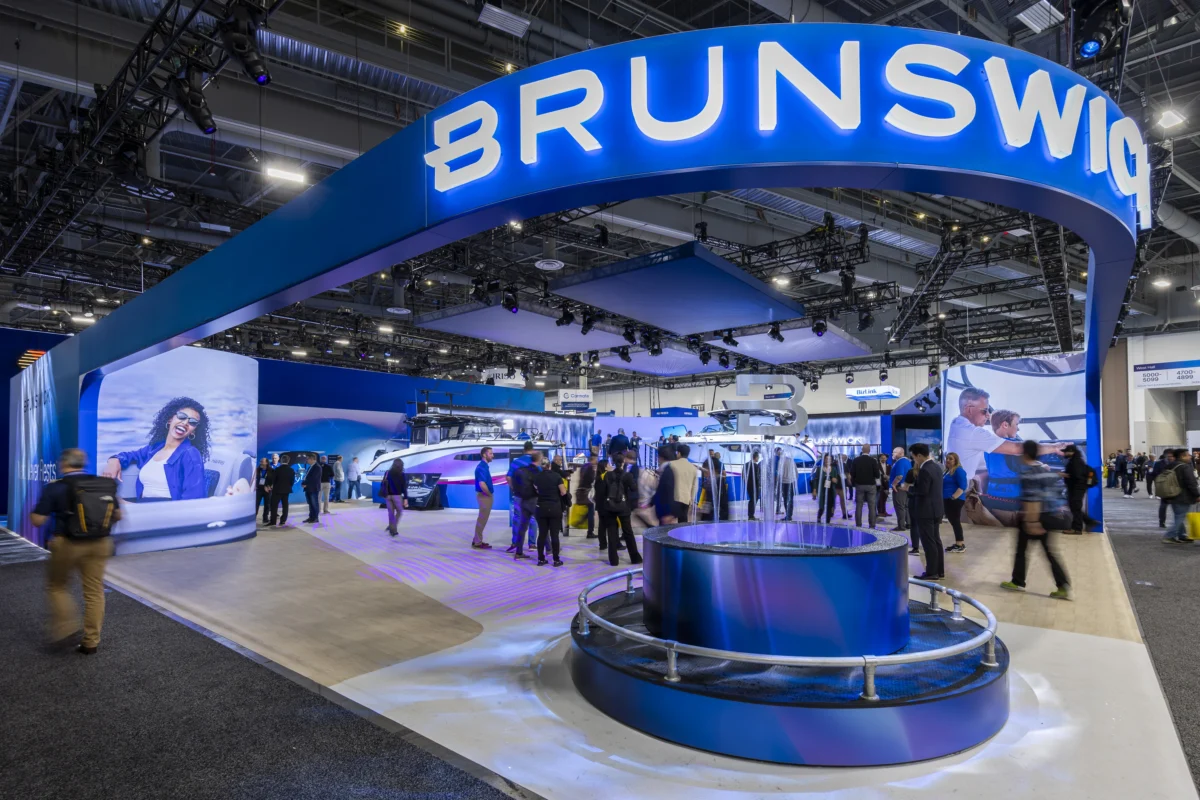 Brunswick XL island exhibit with suspended branding, large digital displays, boats, and a central water feature