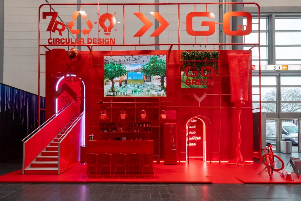 GO Exhibitions double-deck exhibit with red lighting, a staircase, bar seating, and sustainability graphics