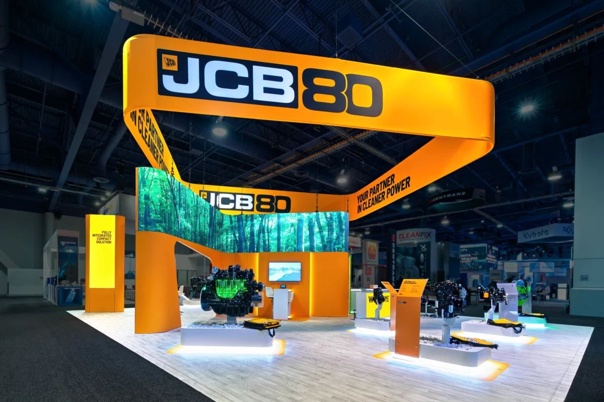 JCB large island exhibit with suspended branding, digital displays, and product showcases