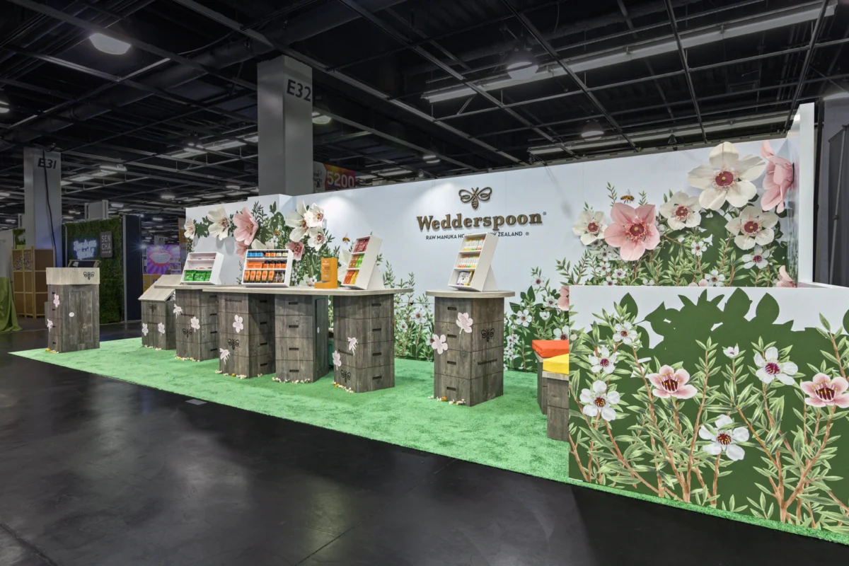 Wedderspoon large in-line exhibit with floral graphics, product displays, and wood-finish counters