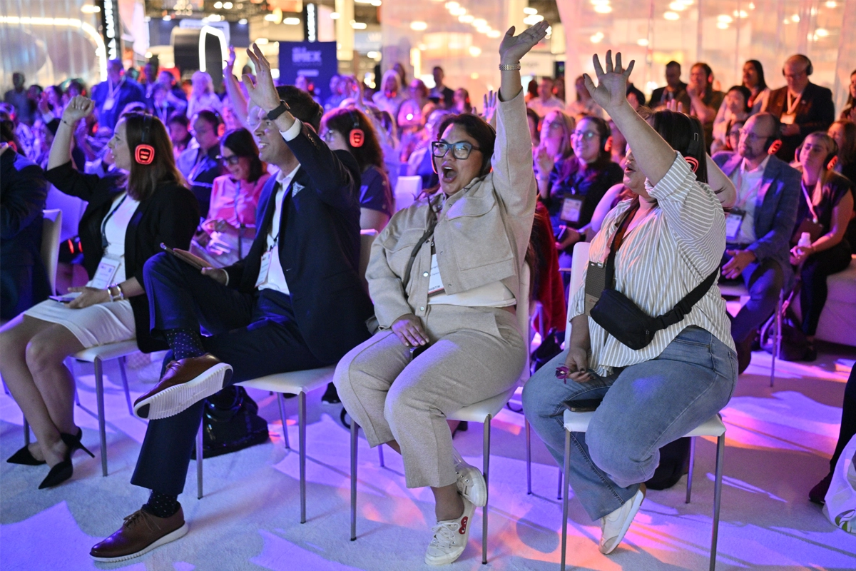 IMEX America education session attendees raise their hands while wearing wireless headphones