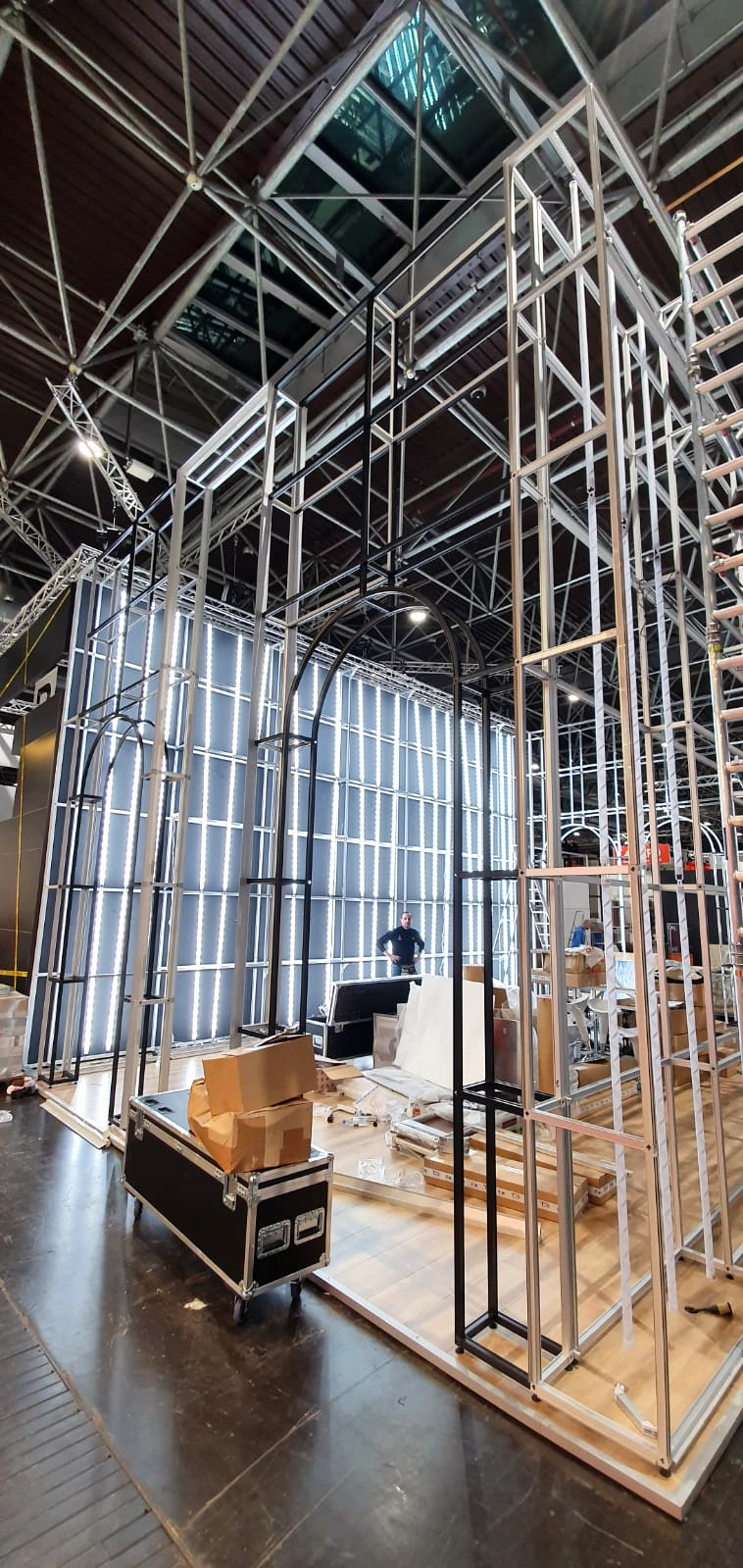 Tall modular tradeshow stand under construction with metal framing and integrated lighting