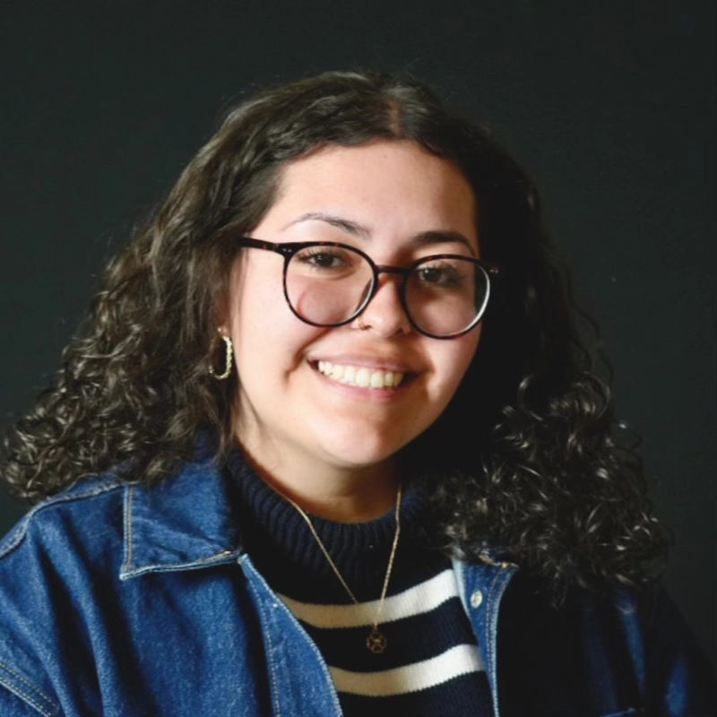 Ariana Castillo smiling in glasses and a denim jacket