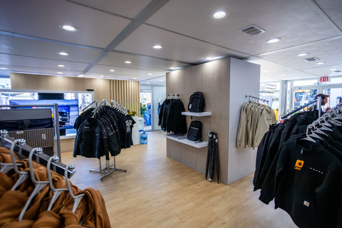 Temporary retail space with jacket racks, backpacks, wood-look flooring, and a finished ceiling