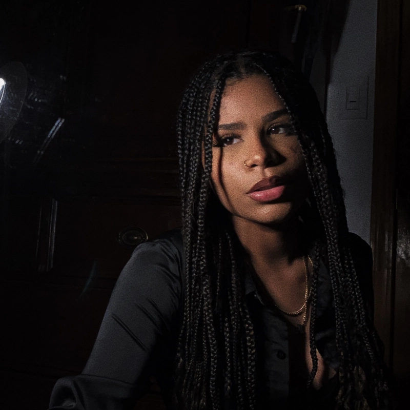 Portrait of Jenny Estevez with long braids, wearing a dark shirt