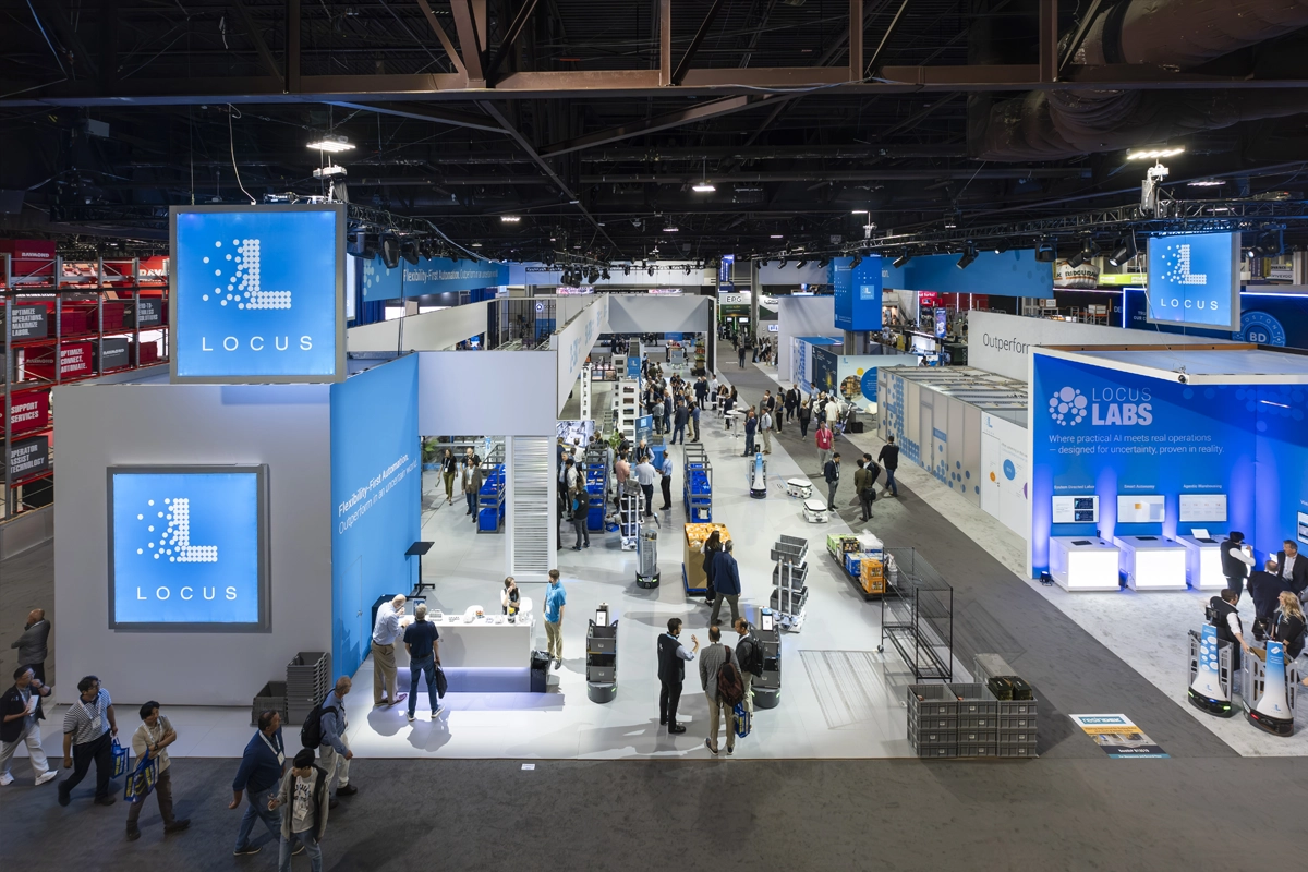Overhead view of attendees and mobile robots in the Locus Robotics exhibit at MODEX 2026.