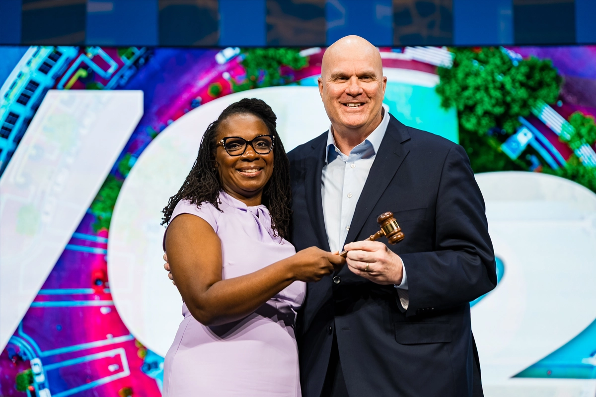 Stacey Church and Brett C. Mitchell hold a gavel together at IAVM’s VenueConnect conference.