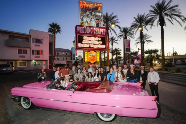 Group posing beside a pink convertible outside Viva Las Vegas Wedding Chapel