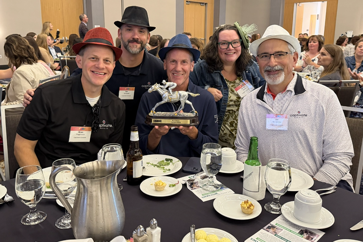 Five Captivate Exhibits team members pose with an award at a banquet