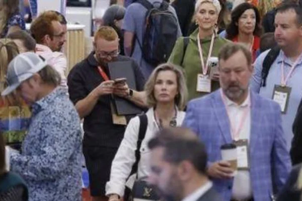 Attendees wearing event badges walk through a crowded tradeshow aisle