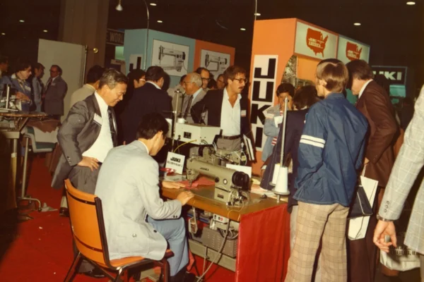 Attendees gather around sewing equipment at the 1976 Bobbin Show at Georgia World Congress Center