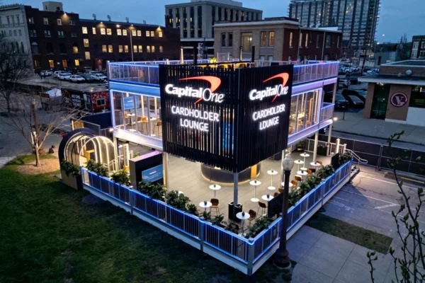 Two-story Capital One Cardholder Lounge with glass walls, outdoor seating, and blue lighting at dusk