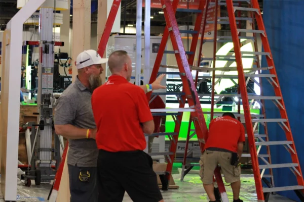 Three workers beside ladders during a tradeshow exhibit installation