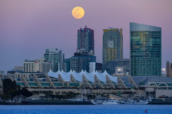 Full moon rising above the San Diego skyline and the tent-like roof of the San Diego Convention Center