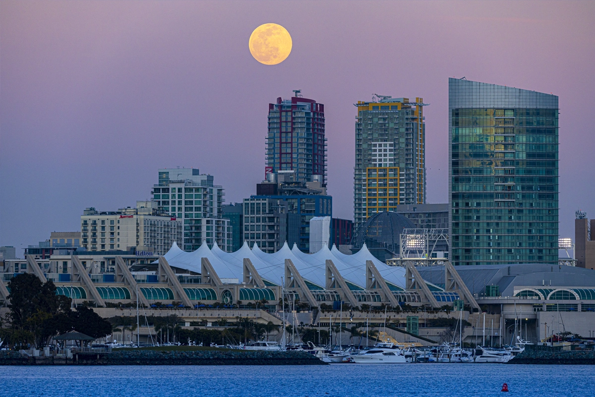 Full moon rising above the San Diego skyline and the tent-like roof of the San Diego Convention Center