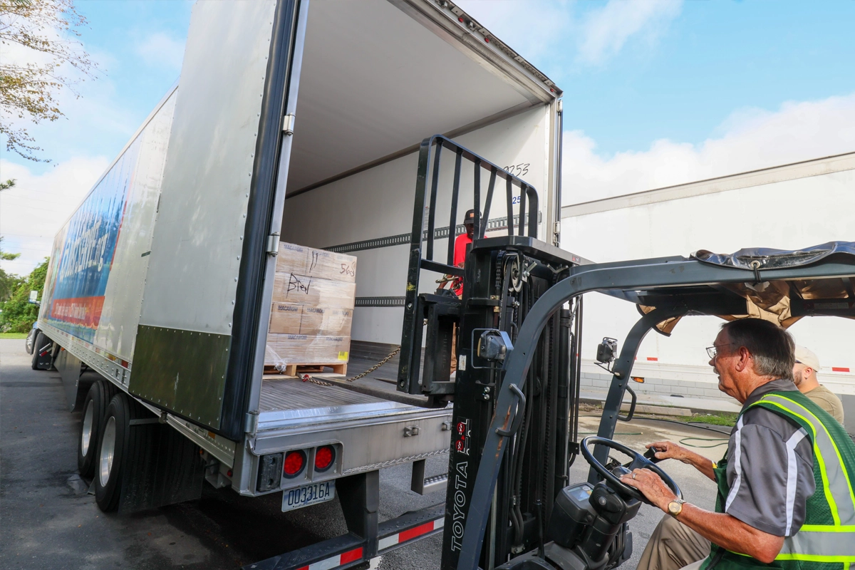 Forklift operator loading a pallet into the back of a freight truck