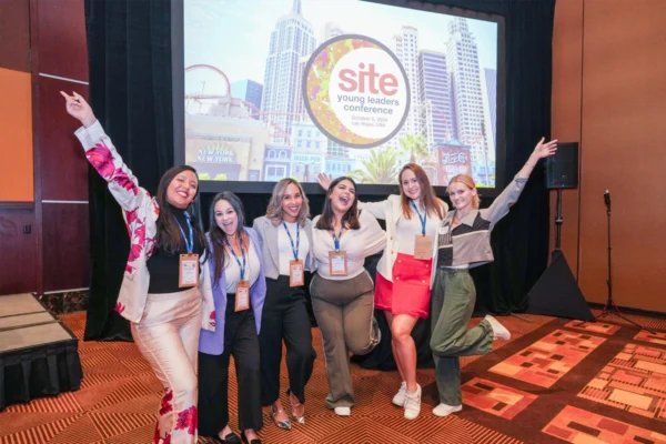 Six attendees pose in front of a SITE Young Leaders Conference screen dated Oct. 8, 2024, in Las Vegas.