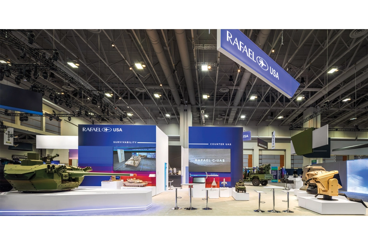 Finished Rafael USA exhibit with military equipment displays, video screens, lighting and an overhead sign