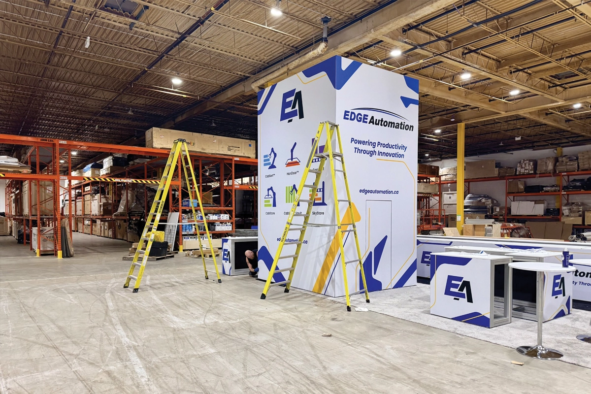 EDGE Automation exhibit components being assembled inside the stevensE3 production facility, with two ladders beside a tall display