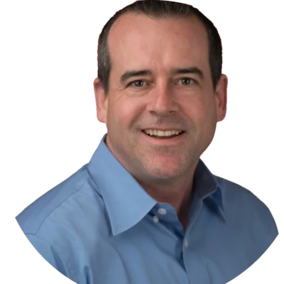 Marc Santos smiles while wearing a blue button-down shirt.