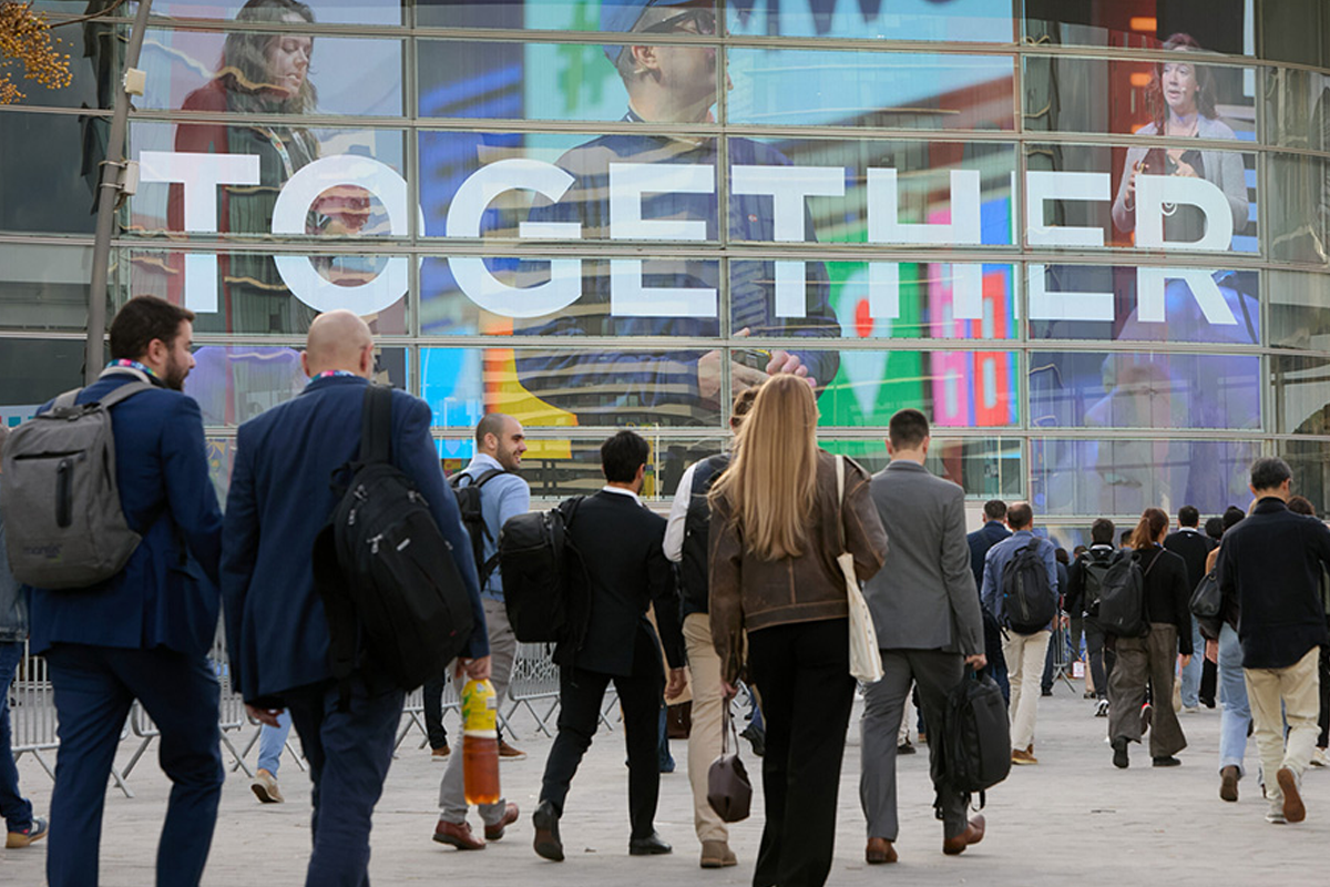 Attendees walk toward a glass-fronted venue beneath a large banner reading “Together.”