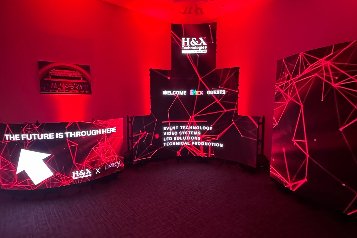 H&X Technologies LED displays illuminated in red show custom screen configurations and welcome graphics for IMEX America guests at a Las Vegas open house.
