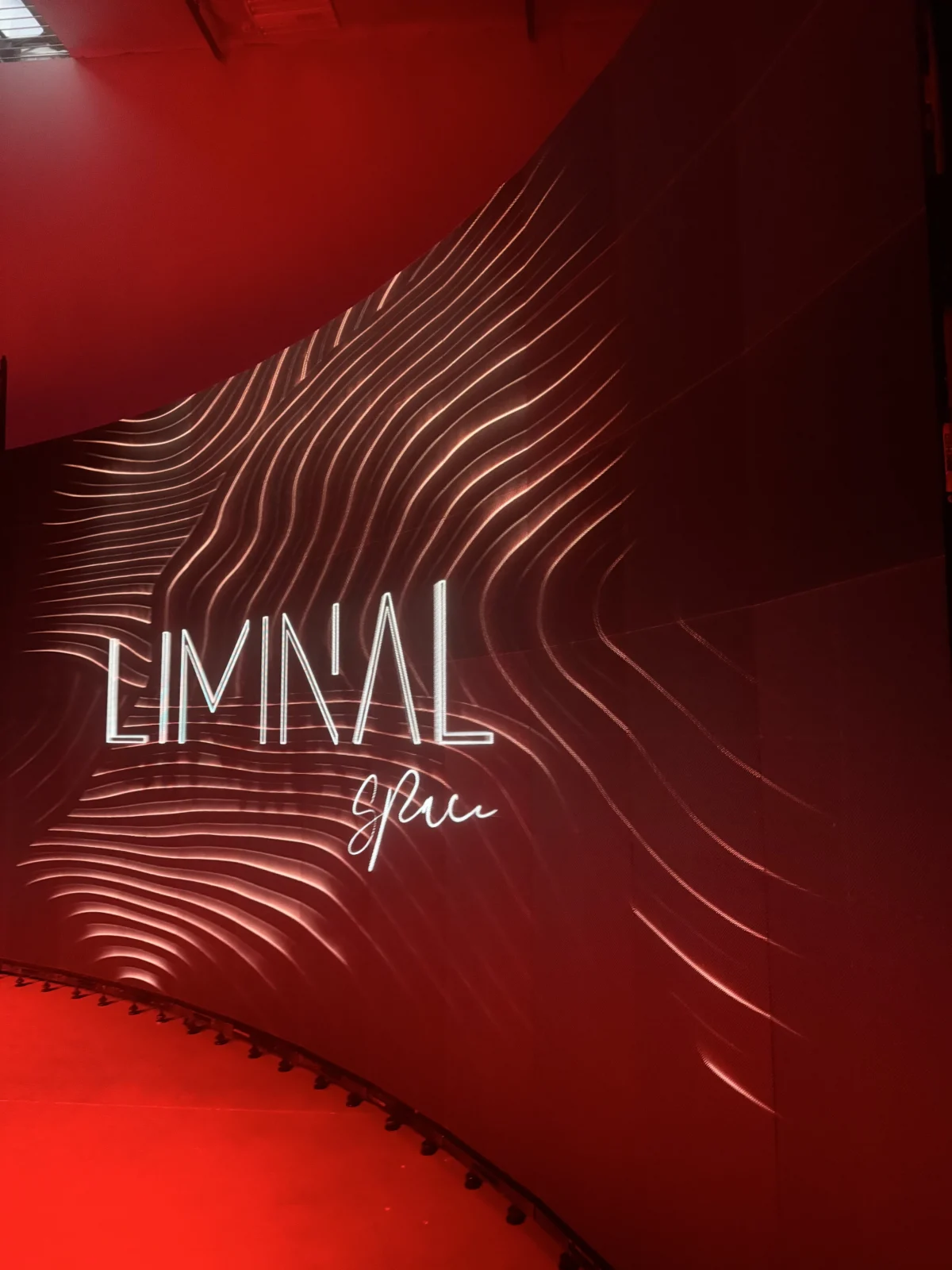 Large curved LED display at H&X Technologies' Las Vegas office featuring Liminal Space branding and flowing red and white graphics.