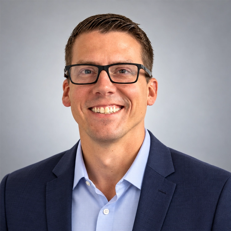 Greg Roberts, operations manager at Superior Logistics, smiles while wearing black glasses, a navy blazer, and a light blue shirt.