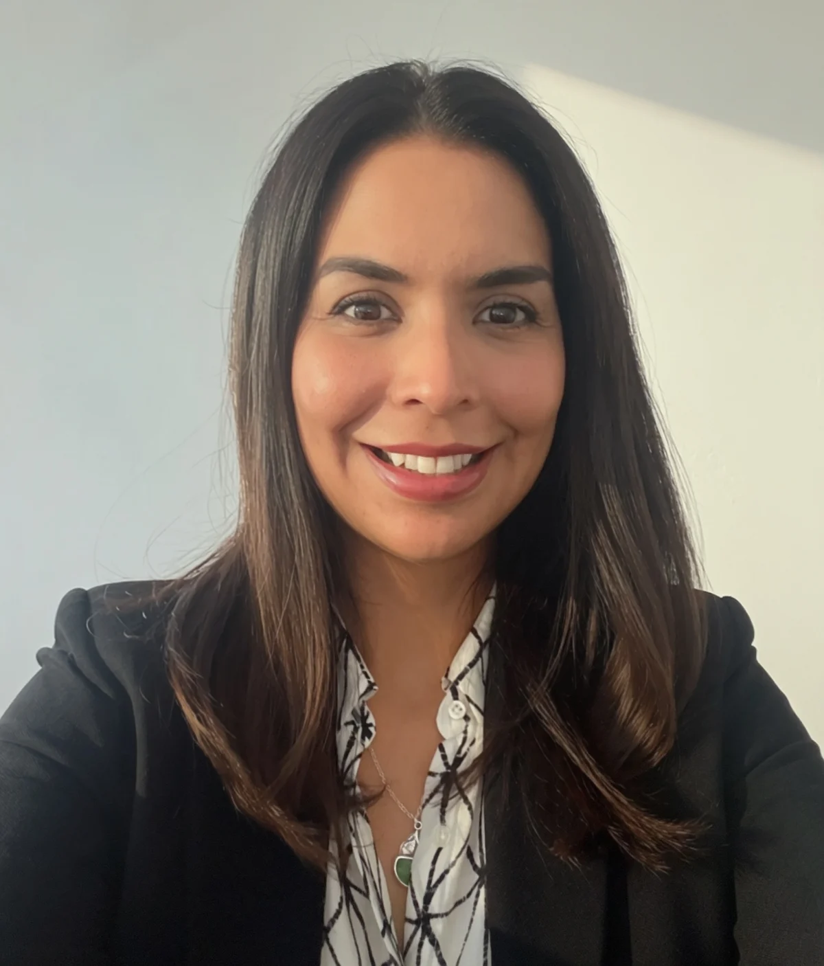Vanessa Sayen smiles in a portrait wearing a black blazer over a patterned blouse.
