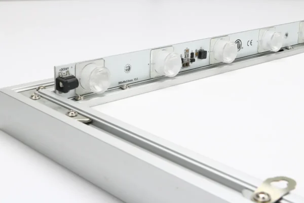 Close-up of an LED lighting strip installed inside an aluminum frame, showing individual lenses, electrical connections, and mounting hardware.