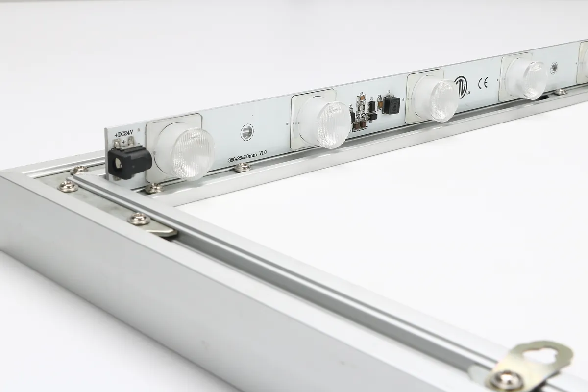 Close-up of an LED lighting strip installed inside an aluminum frame, showing individual lenses, electrical connections, and mounting hardware.